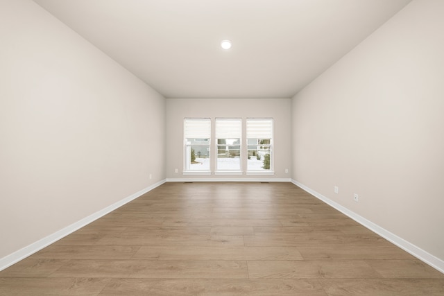 empty room featuring light wood finished floors, recessed lighting, and baseboards