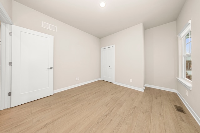 unfurnished room featuring baseboards, visible vents, and light wood finished floors