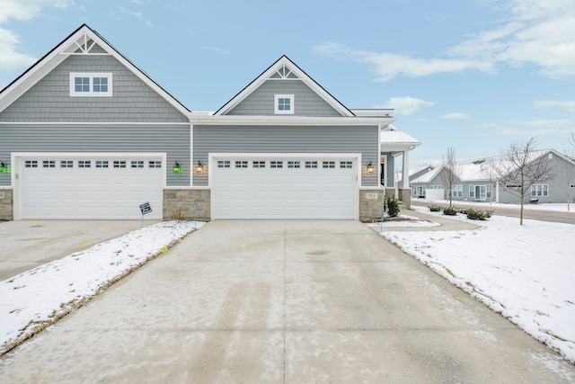 view of front of home with driveway, stone siding, and an attached garage