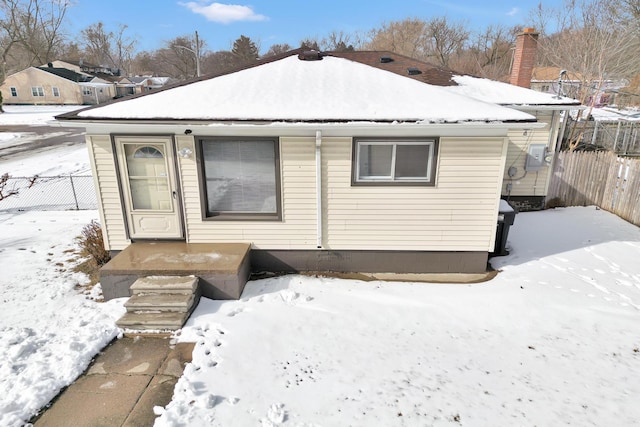 snow covered rear of property with fence