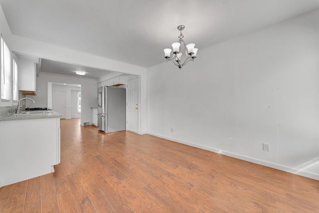 interior space featuring an inviting chandelier, baseboards, a sink, and wood finished floors