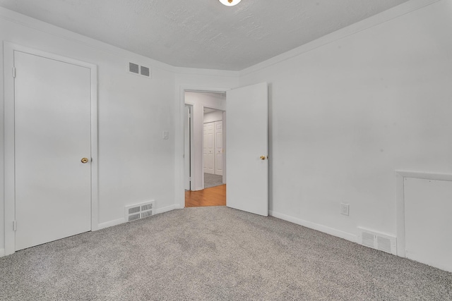 unfurnished bedroom with carpet floors, visible vents, and a textured ceiling