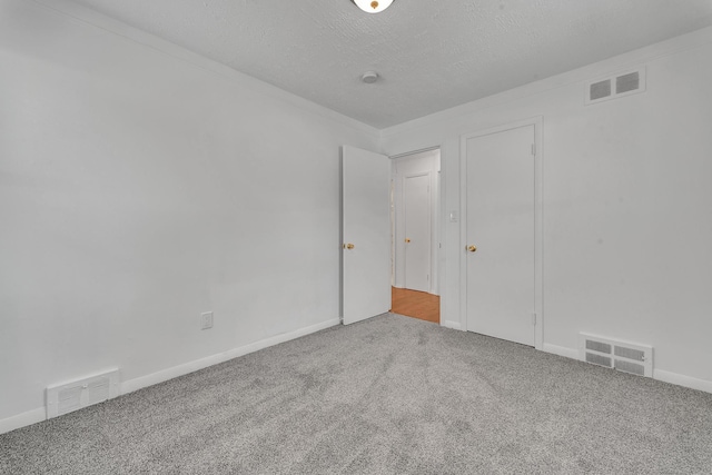 interior space featuring a textured ceiling, carpet flooring, and visible vents