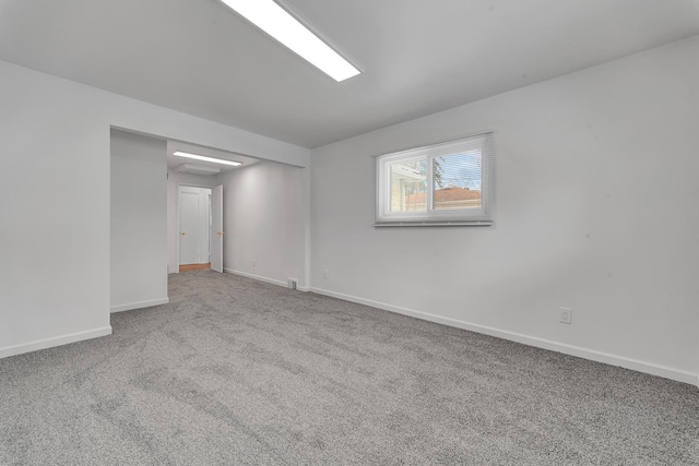 carpeted spare room featuring baseboards