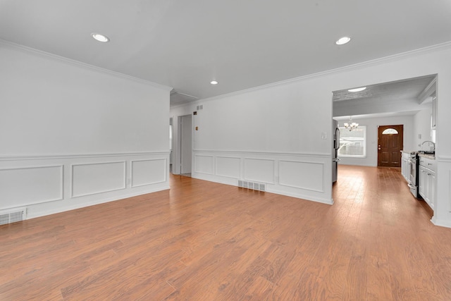 unfurnished room featuring a chandelier, ornamental molding, wood finished floors, and visible vents