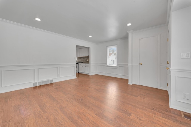 interior space featuring ornamental molding, wood finished floors, visible vents, and recessed lighting