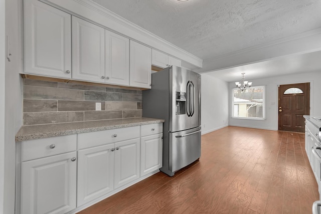 kitchen with stainless steel fridge, white cabinets, dark wood-type flooring, a chandelier, and backsplash