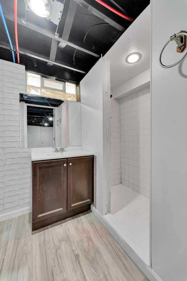 bathroom featuring tiled shower, wood finished floors, and vanity