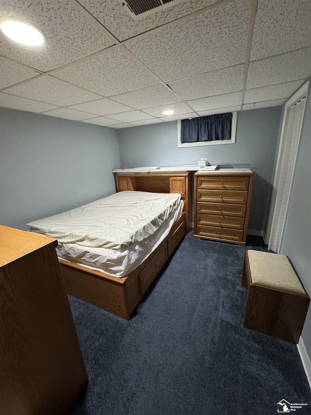 bedroom featuring dark colored carpet, a drop ceiling, visible vents, and baseboards