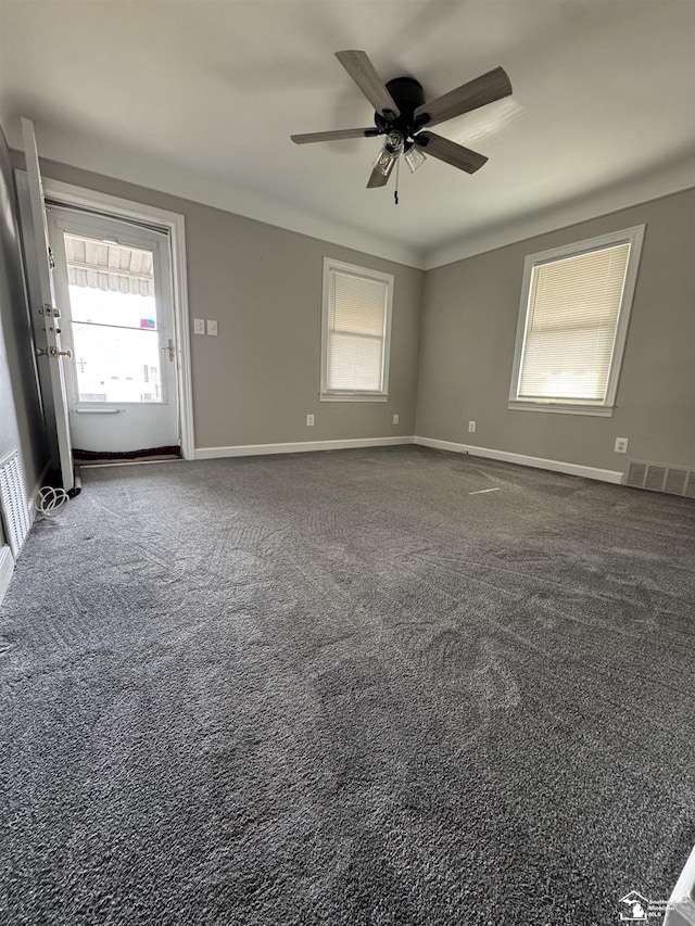 carpeted spare room with baseboards, visible vents, and ceiling fan