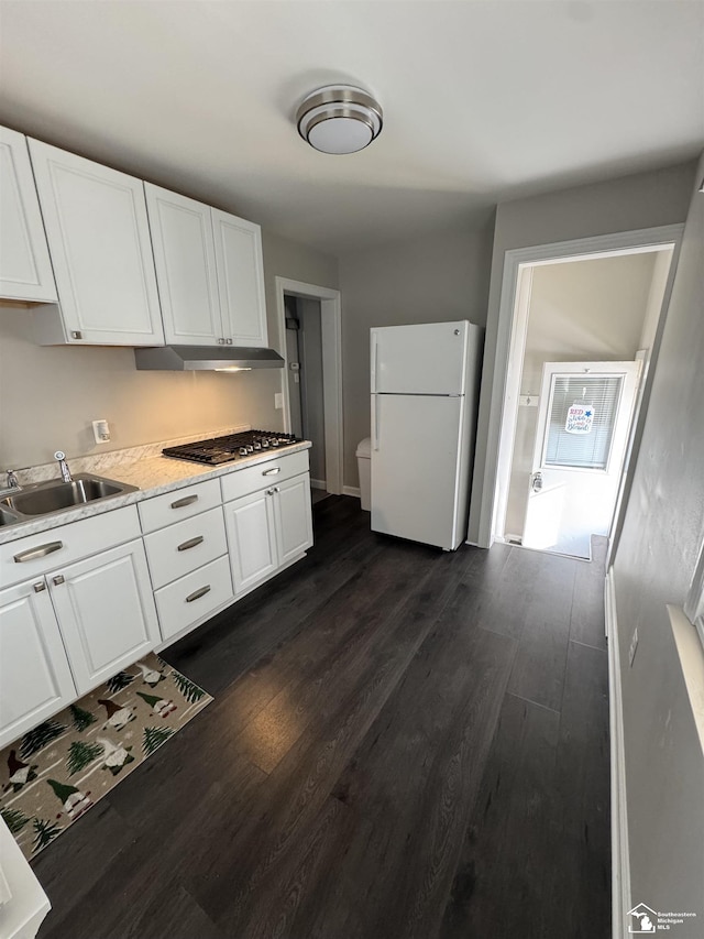 kitchen with under cabinet range hood, white cabinetry, dark wood-style flooring, and freestanding refrigerator