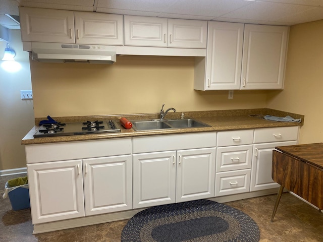 kitchen featuring under cabinet range hood, a sink, white cabinets, dark countertops, and stainless steel gas stovetop