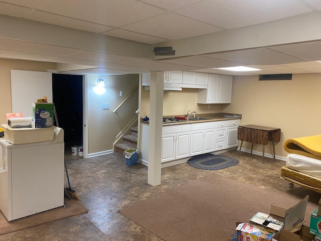 interior space featuring a paneled ceiling, a sink, baseboards, stairs, and washer / dryer