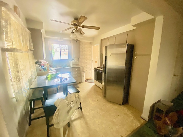 kitchen featuring white gas stove, a ceiling fan, and freestanding refrigerator