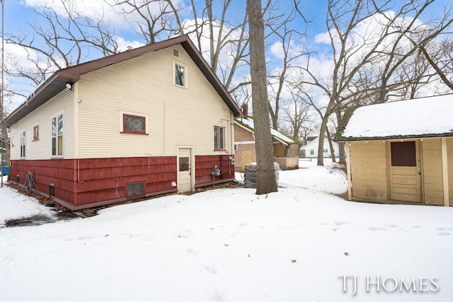 snow covered property with an outbuilding