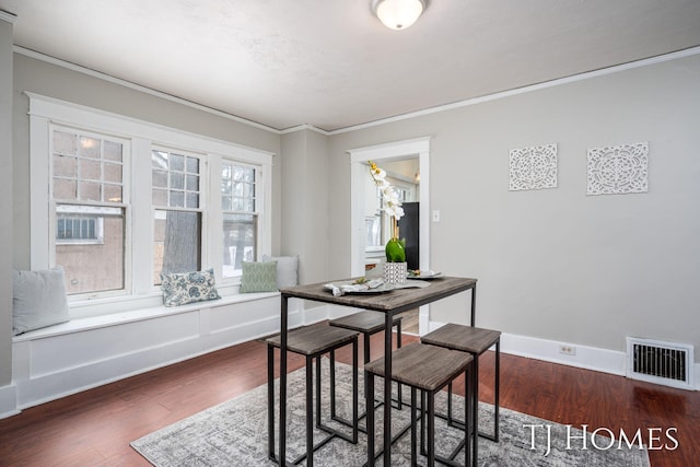 dining room with dark wood-style floors, baseboards, visible vents, and ornamental molding