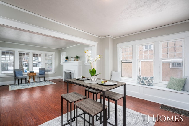 dining area featuring baseboards, dark wood-style floors, ornamental molding, a textured ceiling, and a fireplace