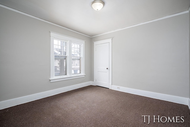 spare room with baseboards, dark colored carpet, and crown molding