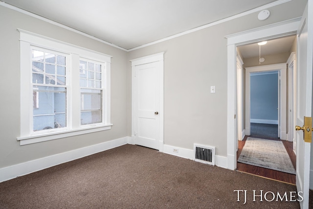 unfurnished bedroom featuring carpet, crown molding, a closet, visible vents, and baseboards