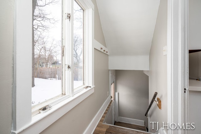 stairs featuring lofted ceiling, baseboards, and wood finished floors