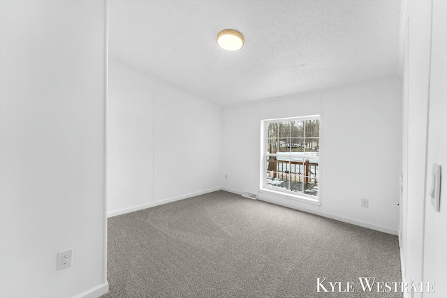 carpeted spare room featuring a textured ceiling, visible vents, and baseboards