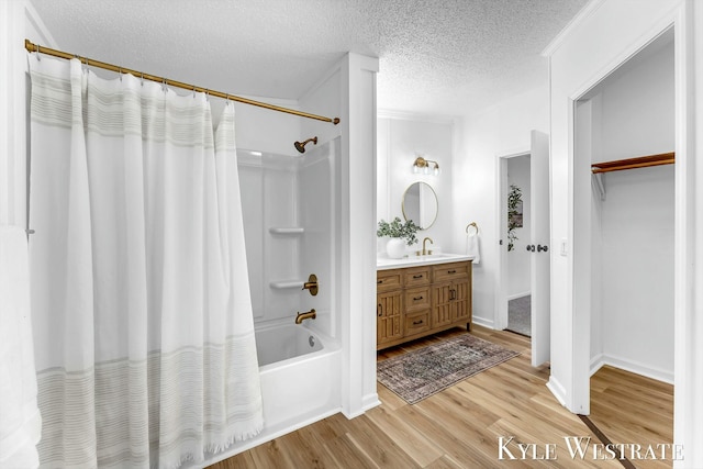 bathroom featuring a textured ceiling, wood finished floors, vanity, and shower / tub combo with curtain