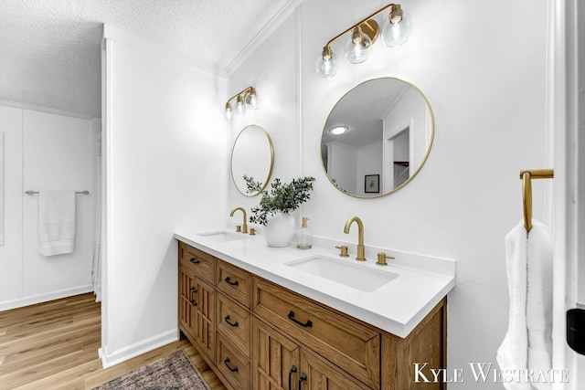 bathroom with a textured ceiling, wood finished floors, and a sink