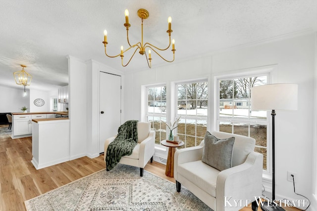 sitting room featuring light wood-style flooring, a notable chandelier, and a textured ceiling