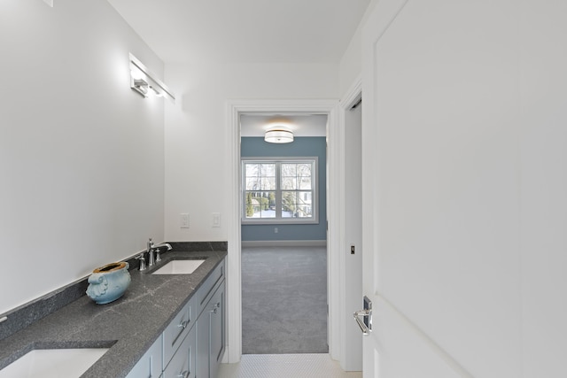 bathroom with double vanity, a sink, and baseboards