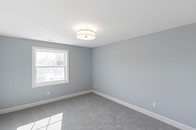 carpeted spare room featuring visible vents and baseboards