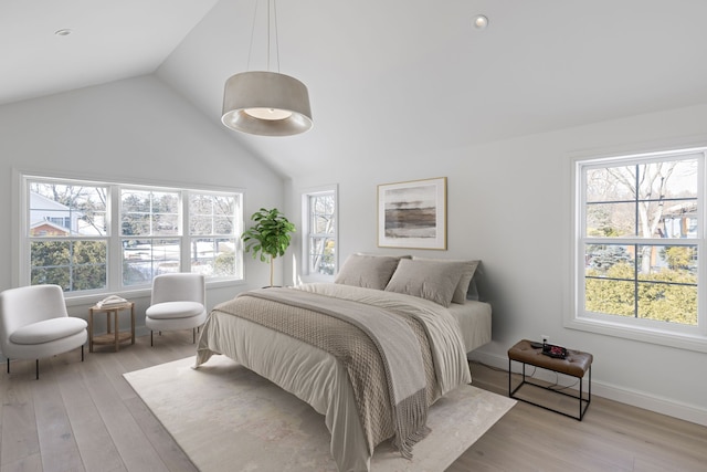 bedroom featuring light wood-style floors, multiple windows, and vaulted ceiling