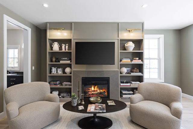 living area featuring a premium fireplace, wood finished floors, and recessed lighting