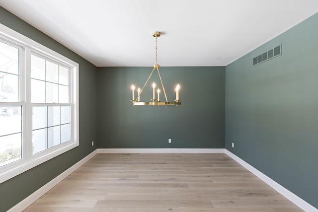 unfurnished room featuring baseboards, visible vents, a chandelier, and light wood-style flooring