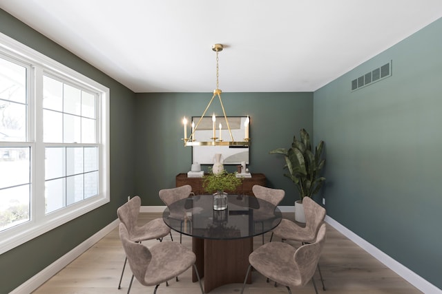 dining room with light wood-style floors, visible vents, and baseboards