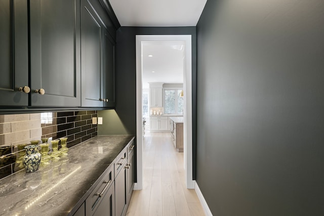 bar with baseboards, light wood finished floors, and decorative backsplash