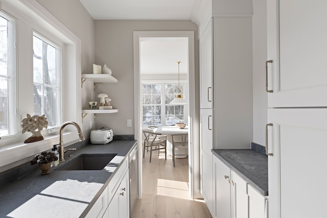 interior space featuring a wealth of natural light, light wood-style flooring, stainless steel dishwasher, and a sink