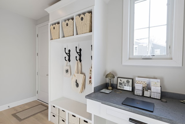 mudroom featuring light wood-style floors, built in study area, and baseboards