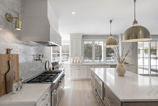 kitchen featuring decorative backsplash, stovetop, a sink, and custom exhaust hood