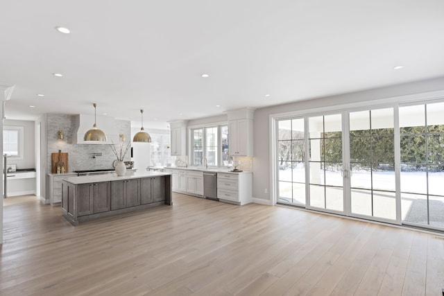 kitchen with light countertops, light wood-style flooring, decorative backsplash, a kitchen island, and dishwasher