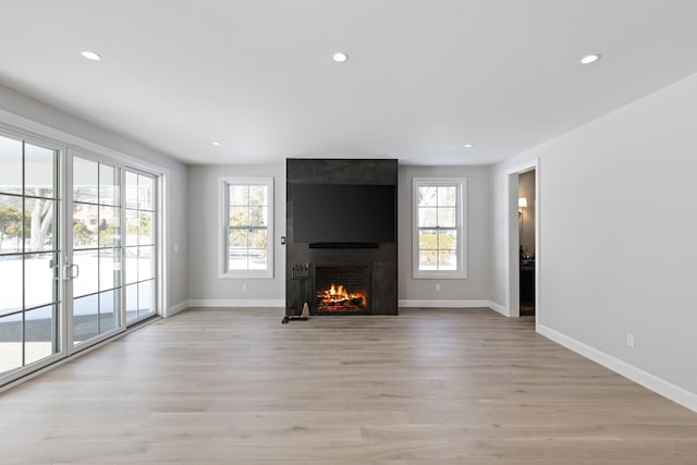 unfurnished living room with light wood-style flooring, a fireplace, baseboards, and recessed lighting