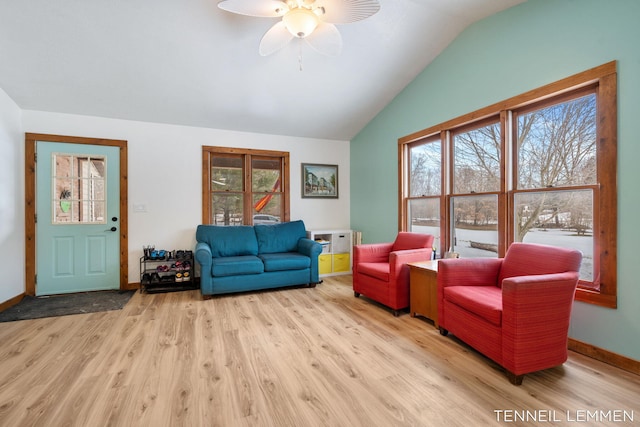 living area featuring lofted ceiling, ceiling fan, baseboards, and wood finished floors