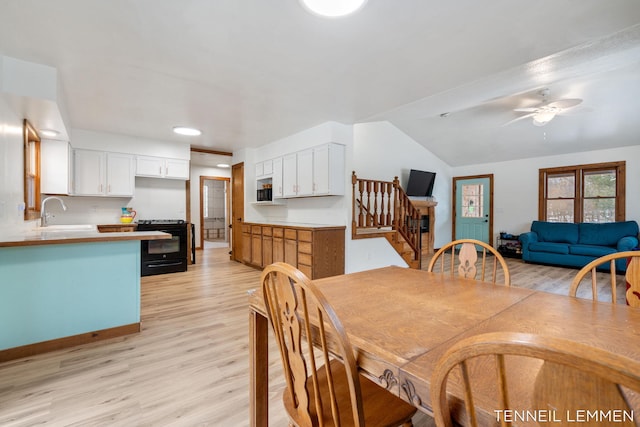 dining space featuring stairway, vaulted ceiling, ceiling fan, and light wood-style flooring