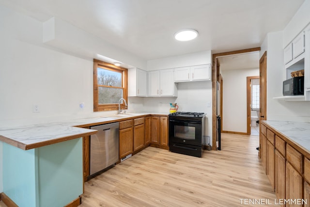 kitchen with a peninsula, light wood-type flooring, black appliances, white cabinetry, and a sink