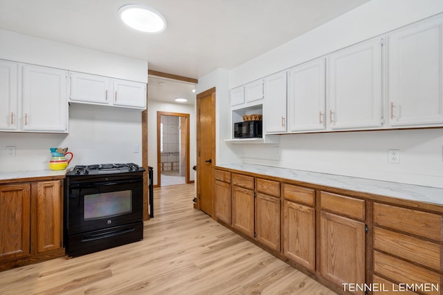 kitchen featuring black gas range, light wood-style floors, white cabinets, and light countertops