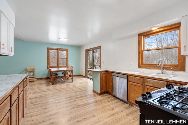 kitchen featuring dishwasher, a sink, light wood-style flooring, and black gas range oven