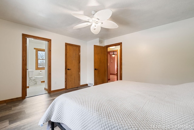 bedroom with wood finished floors, a ceiling fan, visible vents, baseboards, and ensuite bath