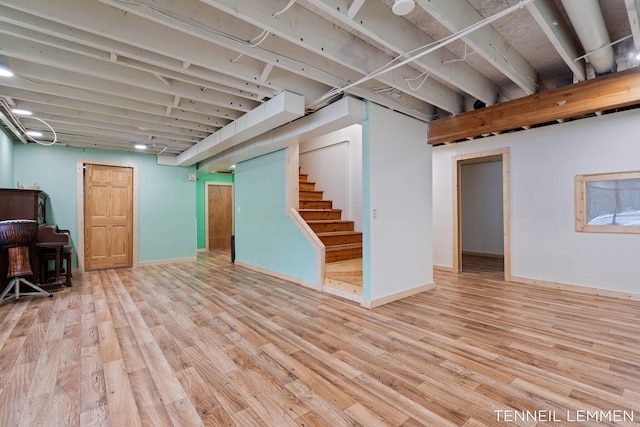 finished below grade area featuring light wood-style floors, baseboards, and stairs