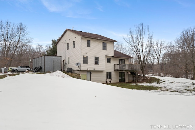 snow covered rear of property with central AC and a wooden deck