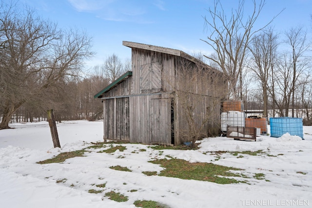 snow covered structure featuring an outdoor structure and a barn