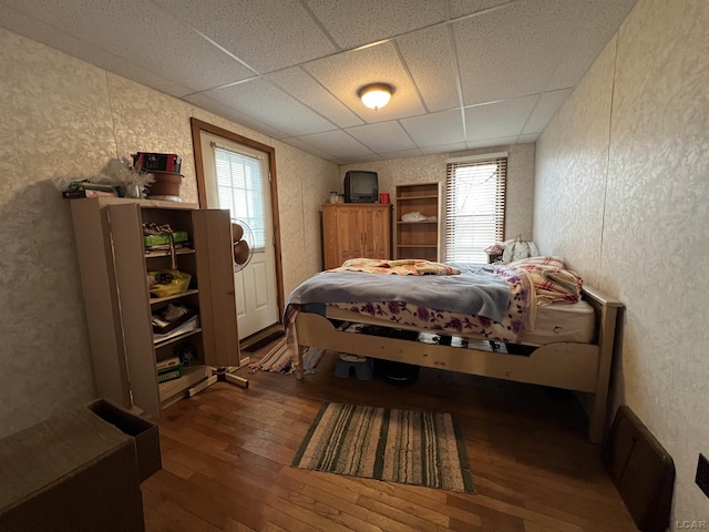 bedroom featuring a textured wall, a drop ceiling, and hardwood / wood-style flooring